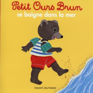 PETIT OURS BRUN SE BAIGNE DANS LA MER.